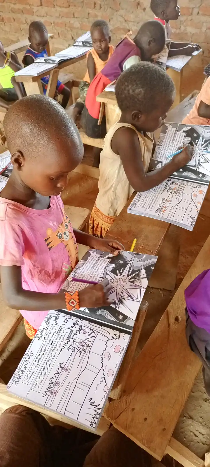 Two children colouring a page of a Bible workbook